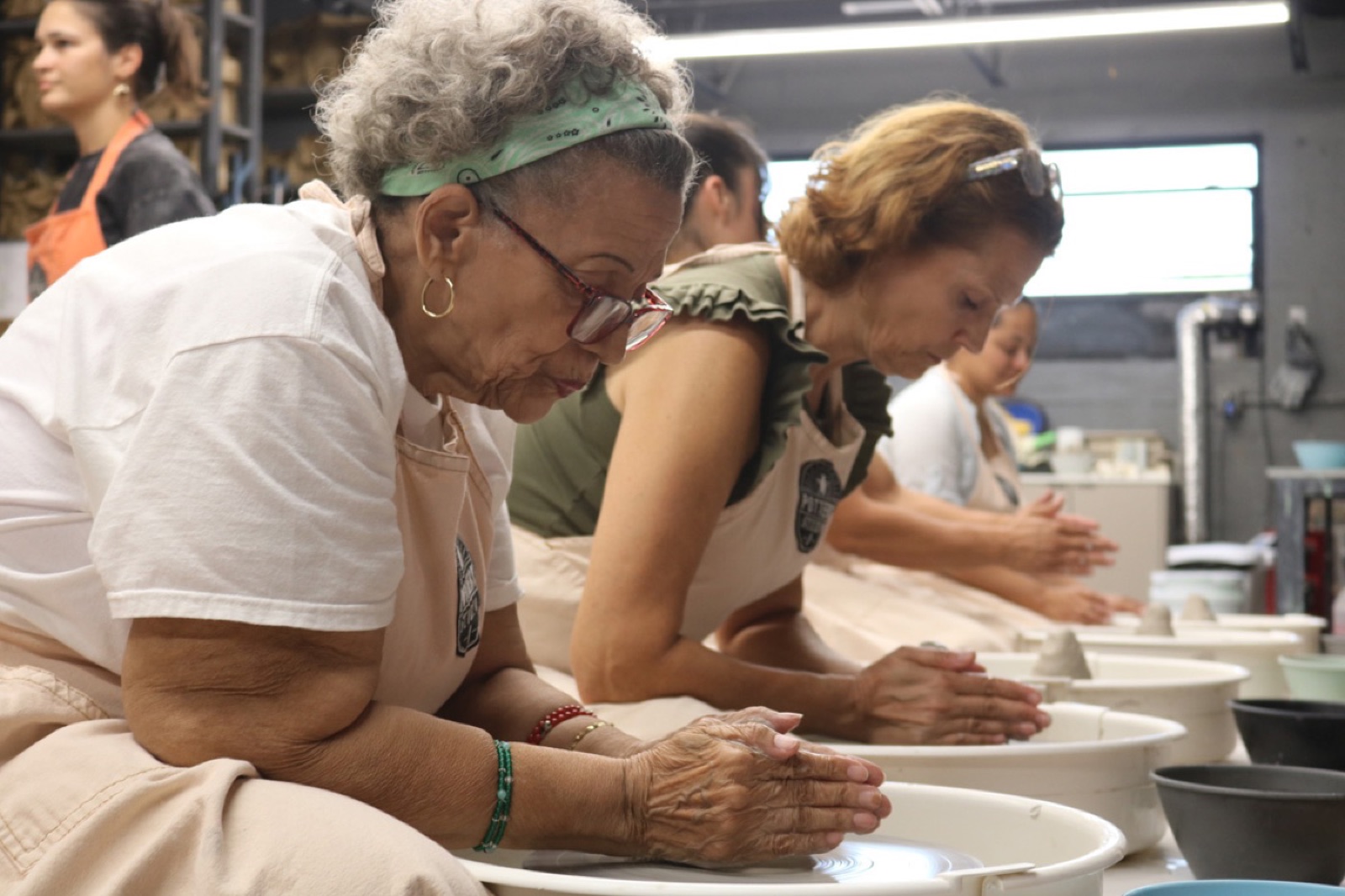 Adults throwing pottery on the wheel