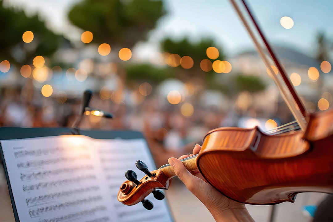 A violinist playing outdoors at dusk, sheet music lit against a garden